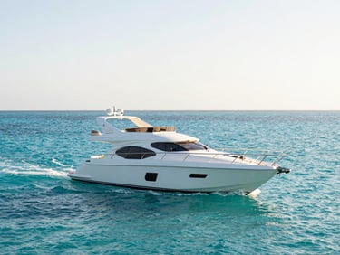A sleek private yacht gliding over clear turquoise Gulf waters, bright golden-hour daylight.