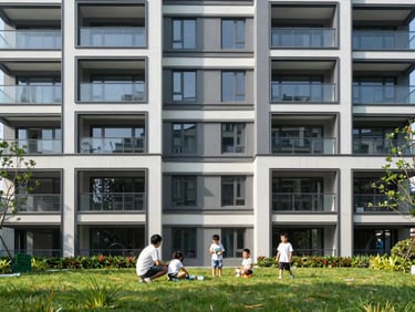Modern residential building facade with clean lines, sunny day, family playing on the grass in the foreground.