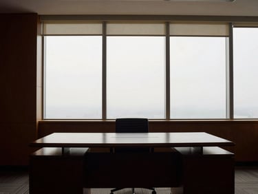 Structured office interior with clean lines, dark mahogany desk, soft overcast daylight through tall windows, 35mm