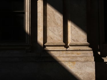 Abstract geometric shadows falling on a neoclassical stone courthouse pillar, high contrast, low-key lighting