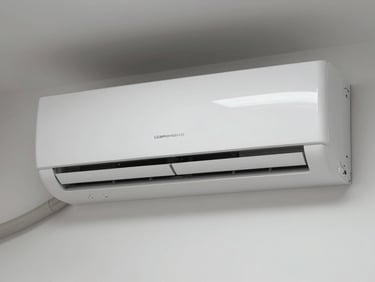 Close-up front view of a white wall-mounted residential split AC unit, mounted on clean interior wall, daylight-balanced indoor lighting, no people