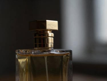 Macro shot of a dark, elegant perfume bottle with a golden cap, catching soft side light, surrounded by a subtle mist, deep charcoal and gold tones, shallow depth of field, 35mm.