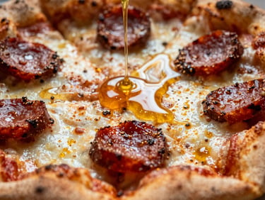 Extreme macro close-up of a pizza slice with glistening hot honey, spicy chorizo, and melted cheese, shallow depth of field.