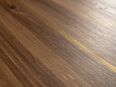 Close-up texture of wood-grain laminate with brushed gold accents, catching warm side-light