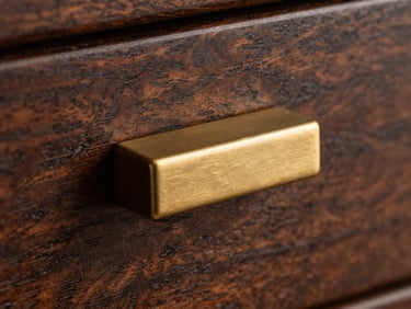 Macro shot of brushed brass drawer pull on dark timber, dramatic side-lighting