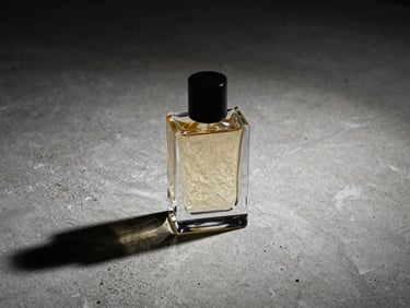 Tight, high-contrast flash photograph of a minimalist perfume bottle casting deep shadows on raw concrete.