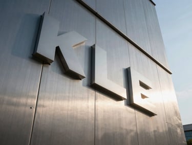Low-angle architectural shot of a massive brushed steel corporate facade sign, crisp morning light highlighting the metallic joints.