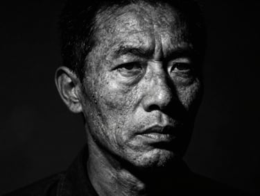 High contrast portrait of a weathered face conveying intense conviction and struggle, deep shadows, single-source side lighting.