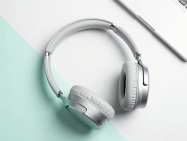 Crisp flat-lay of modern aluminum laptop and wireless headphones on a clean mint background, soft studio light, overhead angle