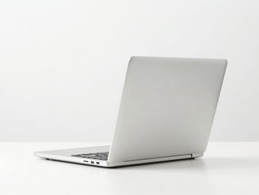 A modern silver laptop open on a crisp white table, bright studio lighting