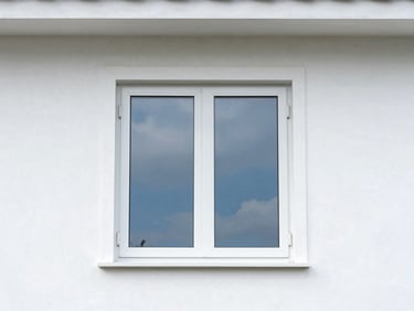 A newly installed double-hung window on a clean white home exterior, reflecting a soft blue sky, sharp construction photography, high-contrast.