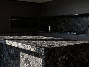 Wide-angle shot of a luxurious kitchen with dark quartz countertops, dramatic side-lighting, high-contrast, sharp focus on the polished stone surface, architectural interior photography.