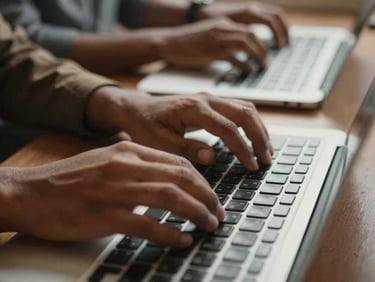 Close-up warm editorial photograph of hands typing on a keyboard during a workshop, natural morning light, rich earthy tones, medium depth of field, authentic documentary style.