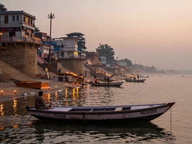 Wide view from a boat on the Ganga at dawn, Varanasi ghats stretching across the frame, oil lamps flickering at the water's edge, soft golden mist over the river