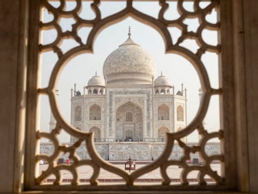 Close-up of Taj Mahal's carved marble lattice screen, intricate floral inlay in warm morning light, shallow depth showing the courtyard behind through the jali pattern
