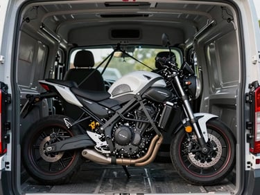 A clean motorcycle secured with heavy-duty tension straps inside a covered transport vehicle, daylight.