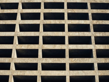 Wide-angle architectural photograph of a modern concrete building facade in Florida, natural daylight, deep navy and gold tones, 35mm