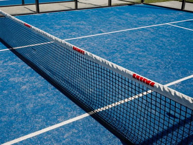 Close-up of a padel court net with red accents, pristine court lines visible under bright sun