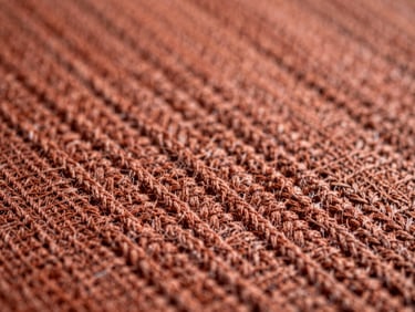 Close-up of a woven cotton tapestry with deep terracotta threads, soft diffused daylight, macro texture, 35mm.