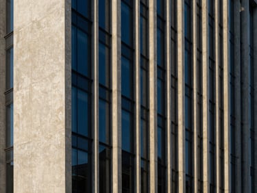 Modern architectural clean concrete and glass office facade, geometric lines, dramatic shadows, corporate scale