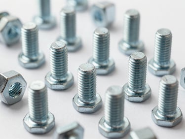 Studio shot of a set of mechanical fasteners and bolts arranged on a white background, even diffused lighting, no shadows obscuring detail, extreme close-up showing surface finish