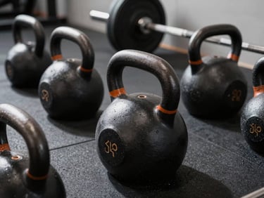 Close-up of heavy iron kettlebells and barbells in a clean modern training facility, dramatic shadows