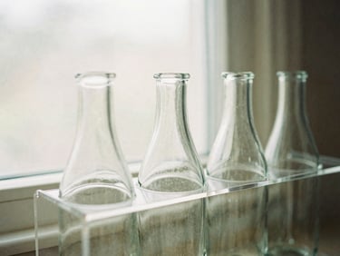 Close-up of styled acrylic under-sink organizers holding glass bottles under diffused window light, 35mm