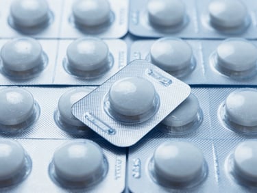Macro shot of batch-certified pharmaceutical blister packs arranged in a precise geometric grid under cool clinical laboratory light, showcasing molecular precision and sterile packaging.