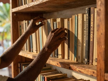 Medium environmental portrait of hands organizing newly cataloged books on a raw timber shelf in a sun-drenched room, warm golden-hour tropical light, 35mm lens.