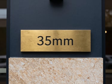 Minimalist architectural detail of a premium corporate entrance with brushed brass signage, overcast daylight, sharp focus, 35mm