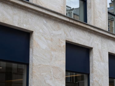Architectural detail of a modern commercial stone facade in London, natural overcast daylight, deep navy shadows, sharp focus, 35mm