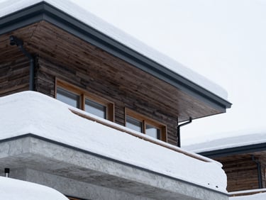 Sharp architectural close-up of a modern Niseko chalet exterior covered in heavy snow, clean technical lines, bright cool winter daylight, 35mm