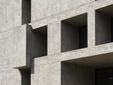 Raw concrete facade with hard graphic shadows under direct sunlight, sharp architectural lines