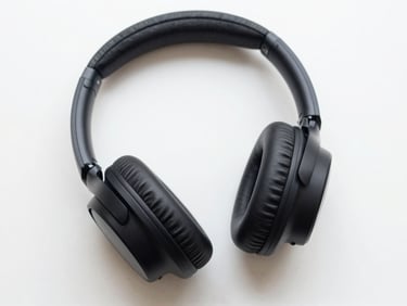 Overhead flat-lay of active noise canceling headphones on a white desk, sharp focus