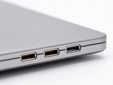 Close-up of USB-C ports on a sleek space gray laptop side, bright studio lighting