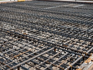 Dense horizontal rebar mesh laid out for a large floor slab, ready for concrete pouring, natural daylight.