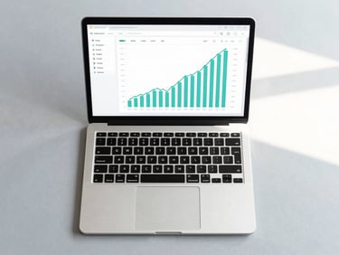Overhead flat-lay of a clean, minimalist digital workspace, a sleek laptop showing a clean financial dashboard with teal and slate line charts, bright natural morning daylight.