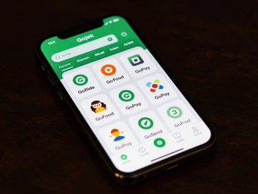 Close-up overhead flat-lay of a smartphone screen displaying a Gojek app status dashboard with multiple service tiles—GoRide, GoFood, GoPay, GoSend—each showing a green active indicator, sharp digital lighting, dark interface background