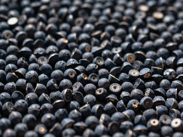 Extreme macro shot of raw polymer pellets in high-contrast daylight, deep slate tones