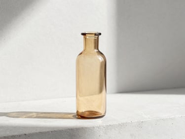 Amber glass diffuser bottle standing on a minimalist concrete ledge, soft shadows, bright natural daylight.