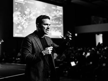 A tech founder in action during a high-stakes presentation, starkly lit modern workspace, high-contrast directional light, deep shadows, 50mm lens