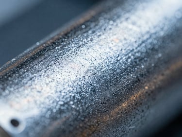 Macro shot of an electroless nickel-plated component, showcasing a dense, even, and highly reflective surface texture, sharp depth of field, cool blue tones.