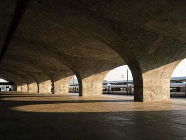 Wide-angle architectural photo of a modern transit terminal, sweeping geometric concrete arches, minimalist composition.