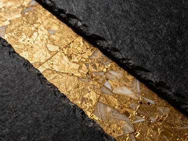 Macro shot of gold-veined marble meeting raw dark slate, high contrast architectural lighting, premium photography