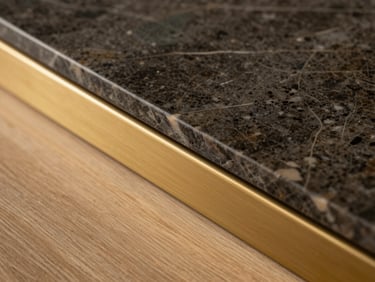 Close-up macro shot of premium materials, a slab of dark marble meeting a brushed brass trim and raw oak floor, warm lighting.
