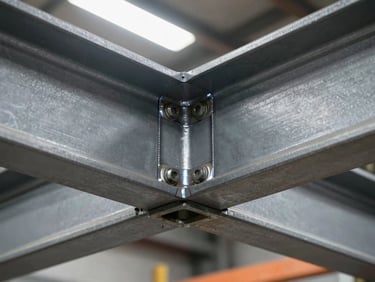 Close-up of steel beam connection detail — bolted joint with visible weld seams, grey industrial finish, bright overhead task lighting, precise metalwork in a construction environment