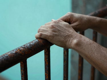 High-contrast film still of hands gripping a rusted iron railing, dramatic cyan backlighting, shallow depth of field.