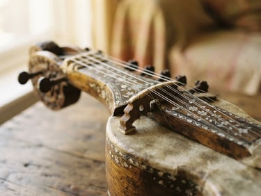 Macro close-up of a traditional dilruba string instrument, soft morning window light, warm golden tones, shallow depth of field, minimalist composition, 35mm