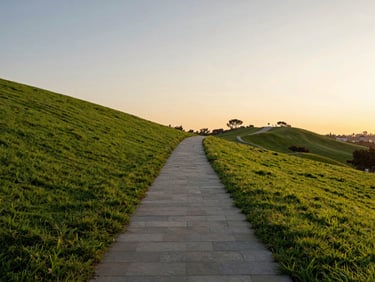 Serene and vast landscape of San Diego Hills memorial park at golden hour, elegant stone pathway leading through lush green lawns, soft warm sunlight, tranquil atmosphere.