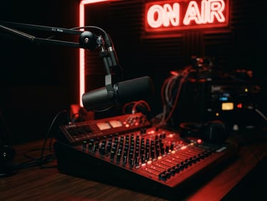 Moody studio photography, dramatic red neon accent lighting, high contrast, professional radio microphone in the foreground with a mixing console blurred in the background, 35mm